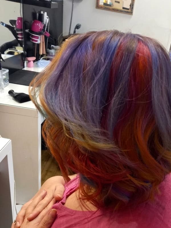 A shoulder-length bob coloured in copper, violet and red tones with a soft curl through the ends
